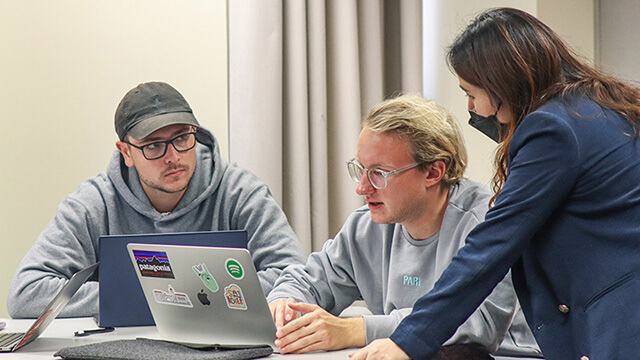 Two students and an instructor conferring at a computer